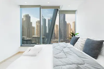 a large white bed in a room with a large window at Gala Guests - Silverene Tower Marina Living Apartments in Dubai