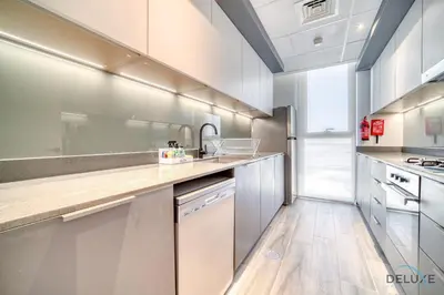 a kitchen with white cabinets and a wooden floor at Tranquil 2BR with Assistant Room at Mesk 1 Midtown Dubai Production City by Deluxe Holiday Homes in Dubai