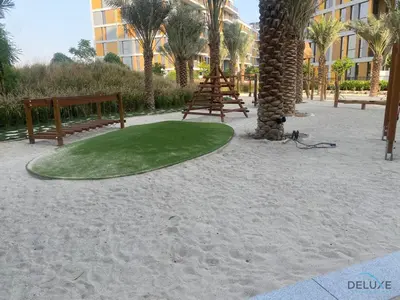 a golf course on the beach with benches and palm trees at Tranquil 2BR with Assistant Room at Mesk 1 Midtown Dubai Production City by Deluxe Holiday Homes in Dubai