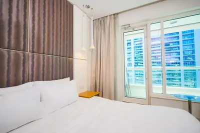 a bedroom with a large white bed and a window at Alashrafia Saray- Splendid 1BR apartment in Canal Views in Dubai