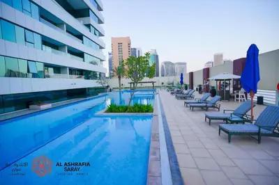 a swimming pool with chaise lounge chairs next to a building at Alashrafia Saray- Splendid 1BR apartment in Canal Views in Dubai