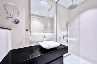 a white bathroom with a sink and a shower at 5* Studio, 10min walk to Dubai Mall, 1min Bay Sqr in Dubai