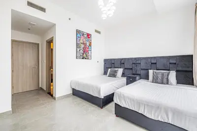 two beds in a room with white walls at Daniels Marina View 4BR Duplex in Stella Maris in Dubai
