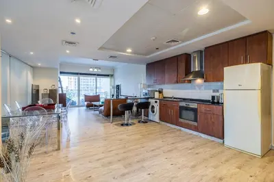 a kitchen with wooden cabinets and a white refrigerator at Spacious Apartment I Lake Views Apartment in JLT I Close To Metro in Dubai