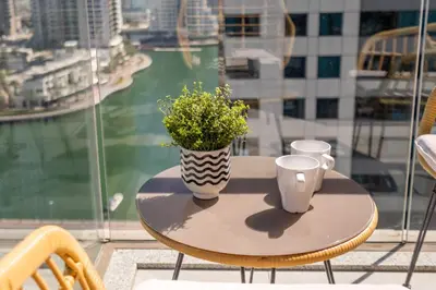a table with two cups and a vase with flowers on it at GuestReady Holiday Homes - Boho Marina Dream in Dubai