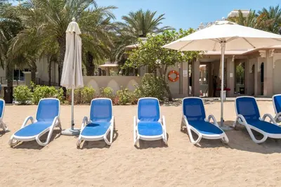 a group of blue chairs and an umbrella on the beach at Spacious 2-bedroom beachfront apartment with pool in Dubai