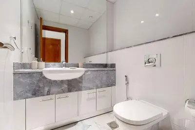 a white bathroom with a sink and a toilet at Meera Tower - Sleek One Bedroom in Dubai