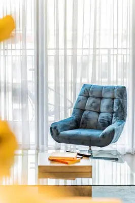 a blue chair sitting in front of a window at Chic 1BR in Park Heights 2 - Dubai Hills in Dubai