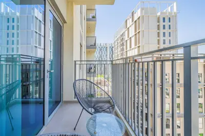 a balcony with a chair and views of buildings at Chic 1BR in Park Heights 2 - Dubai Hills in Dubai