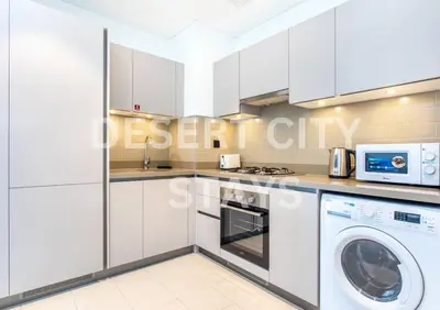 a kitchen with white cabinets and a washer and dryer at 2 Bed in Sobha Creek Vista Reserve with Burj Khalifa views hosted by Desert City Stays in Dubai