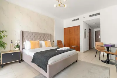 a bedroom with a large bed with a desk and chairs at Silkhaus spacious studio in Boulevard Central with gym & pool in Dubai