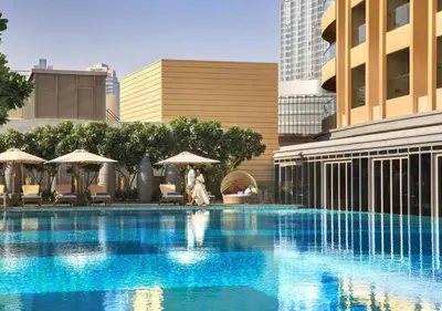 a woman walking by a swimming pool in a city at Deluxe - Address Dubai Mall - The Residence in Dubai