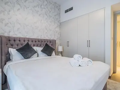 a bedroom with a large white bed with towels on it at Stylish 1BR in Park Heights 2 - Dubai Hills in Dubai