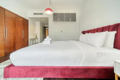 a bedroom with a large white bed with a red rug at South Ridge 2, Downtown Dubai - Mint Stay in Dubai