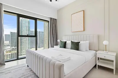 a white bedroom with a large bed and a large window at Silkhaus elegant 1BDR in Downtown premium tower in Dubai
