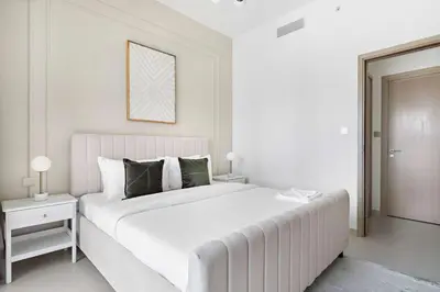 a white bedroom with a large white bed with green pillows at Silkhaus elegant 1BDR in Downtown premium tower in Dubai