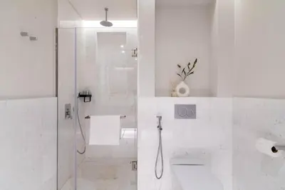 a white bathroom with a shower and a toilet at GuestReady - Bejeweled Studio at The Palm Tower in Dubai