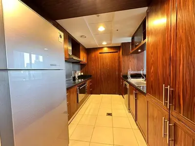 a large kitchen with wooden cabinets and a refrigerator at Durrani Homes - Supreme 5BR besides Dubai Mall With Burj Khalifa and Fountain view in Dubai