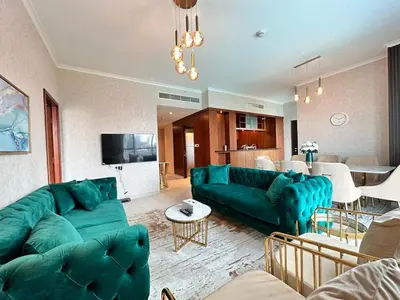 a living room with green couches and a kitchen at Durrani Homes - Supreme 5BR besides Dubai Mall With Burj Khalifa and Fountain view in Dubai