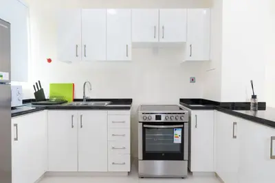 a white kitchen with a stove and white cabinets at Calm Aesthetic 3 Bedroom Villa in Dubai