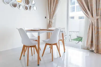 a dining room table with white chairs and a window at Calm Aesthetic 3 Bedroom Villa in Dubai