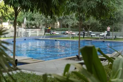 a large swimming pool with people laying on chairs around it at Bellavista - Dazzling High Floor - 2BR - 29 BOULEVARD - Burj Khalifa & Fountain View in Dubai