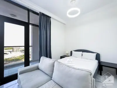 a bedroom with a bed and a couch and a window at NEW! Amazing Studio in Al Majan in Dubai