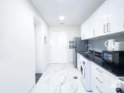a kitchen with white cabinets and a microwave at NEW! Amazing Studio in Al Majan in Dubai
