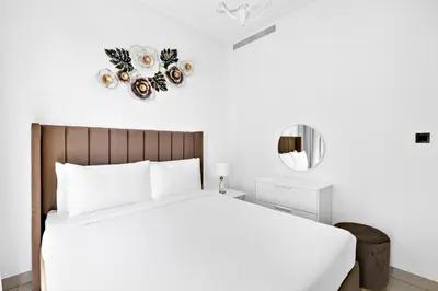 a white bedroom with a large bed and a mirror at ALiving Luxury 1BR I Partial Burj khalifa Views I Sobha Creek Vista in Dubai