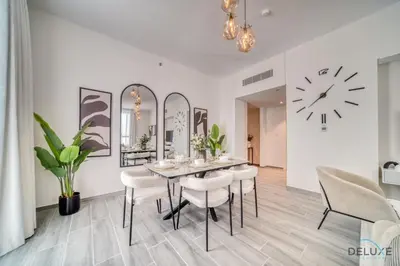 a dining room with a table and chairs and a clock at Placid 2BR with Assistant Room at Mesk 1 Midtown Dubai Production City by Deluxe Holiday Homes in Dubai
