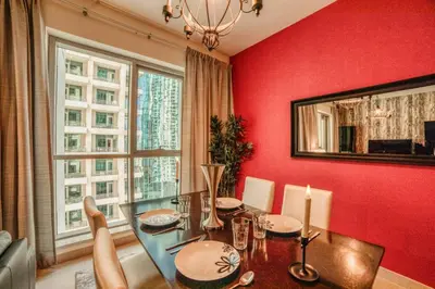 a dining room with a glass table and a red wall at Bellavista - Ultra Modern - 2BR - Boulevard Central - Burj Khalifa View in Dubai