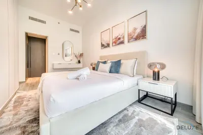 a white bedroom with a large bed and a table at Exquisite 2BR with Assistant Room at Mesk 1 Midtown Dubai Production City by Deluxe Holiday Homes in Dubai