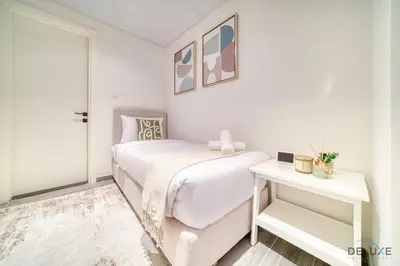 a white bedroom with a bed and a table at Exquisite 2BR with Assistant Room at Mesk 1 Midtown Dubai Production City by Deluxe Holiday Homes in Dubai