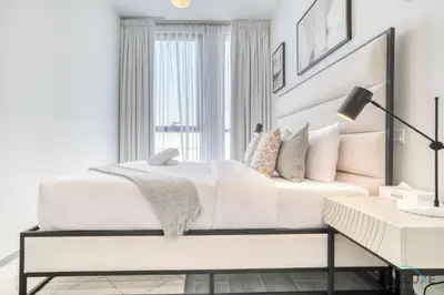 a white bedroom with a white bed and a desk at Impressive 2BR with Assistant Room at Mesk 1 Midtown Dubai Production City by Deluxe Holiday Homes in Dubai