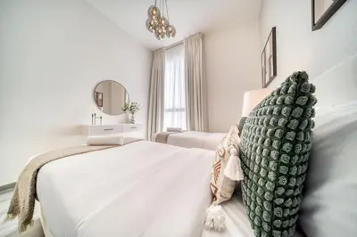 a white bedroom with a bed and a mirror at Alluring 2BR with Assistant Room at Mesk 1 Midtown Dubai Production City by Deluxe Holiday Homes in Dubai