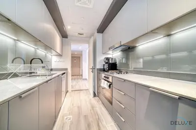 a large kitchen with stainless steel appliances and wood floors at Harmonious 2BR with Assistant Room at Mesk 1 Midtown Dubai Production City by Deluxe Holiday Homes in Dubai