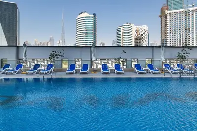a pool with blue lounge chairs on the roof of a building at Royal Maison Luxurious 2 Br in Business Bay in Dubai