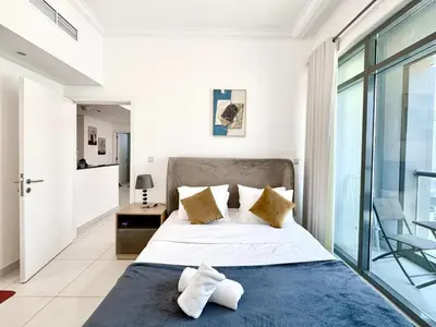 a bedroom with a large bed and a balcony at Royal Maison Deluxe 2 Br in Executive Bay in Dubai