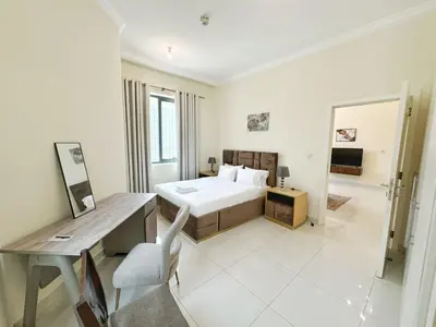 a white bedroom with a bed and a desk at Royal Maison Deluxe 2 Br in Executive Bay in Dubai