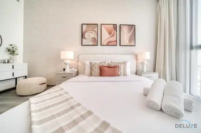 a white bedroom with a large white bed and two lamps at Suave 2BR with Assistant Room at Mesk 1 Midtown Dubai Production City by Deluxe Holiday Homes in Dubai
