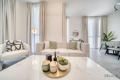 a white living room with a couch and a table at Refined 2BR with Assistant Room at Mesk 1 Midtown Dubai Production City by Deluxe Holiday Homes in Dubai