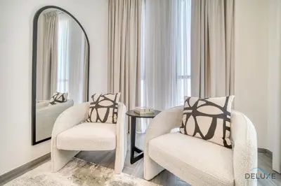 a living room with two chairs and a mirror at Refined 2BR with Assistant Room at Mesk 1 Midtown Dubai Production City by Deluxe Holiday Homes in Dubai