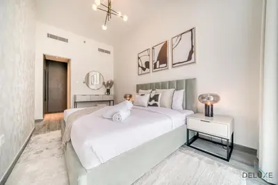 a white bedroom with a large bed and a table at Refined 2BR with Assistant Room at Mesk 1 Midtown Dubai Production City by Deluxe Holiday Homes in Dubai
