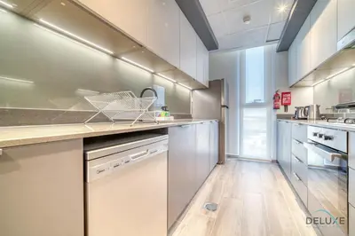 a large kitchen with stainless steel appliances and wooden floors at Charming 2BR with Assistant Room at Mesk 1 Midtown Dubai Production City by Deluxe Holiday Homes in Dubai