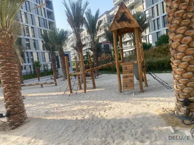 a playground in the sand in front of a building at Charming 2BR with Assistant Room at Mesk 1 Midtown Dubai Production City by Deluxe Holiday Homes in Dubai
