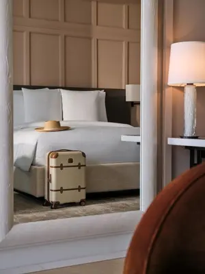 a bedroom with a bed with a suitcase on the floor at The Lana - Dorchester Collection in Dubai