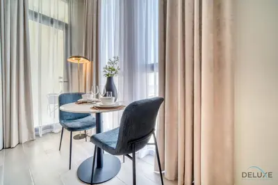 a dining room with a table and chairs next to a window at Striking Studio at Mesk 1 Midtown Dubai Production City by Deluxe Holiday Homes in Dubai
