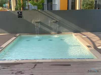 a swimming pool with a water fountain at Striking Studio at Mesk 1 Midtown Dubai Production City by Deluxe Holiday Homes in Dubai