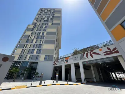 a tall building with a parking lot in front of it at Prime Studio at Mesk 1 Midtown Dubai Production City by Deluxe Holiday Homes in Dubai