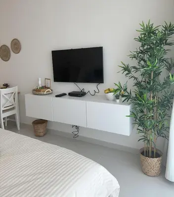 a white entertainment center with a tv on a white wall at Tranquil Studio in Damac Hills in Dubai